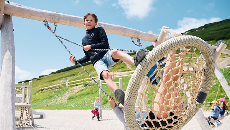 Spaß am Kletterspielplatz, © NB/Wegerbauer Bub steht auf Schaukel am Spielplatz