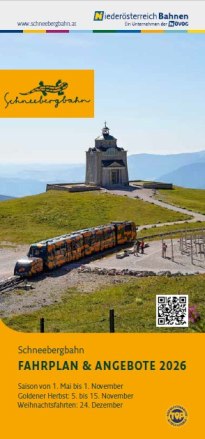 Zug der Schneebergbahn auf Bergstrecke vor Bergstation mit Geb&auml;ude, im Hintergrund blauer Himmel.